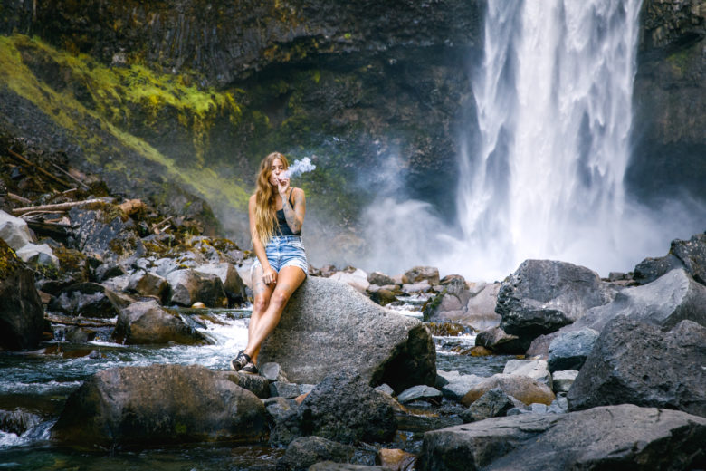 Cute girl smoking cannabis by waterfall